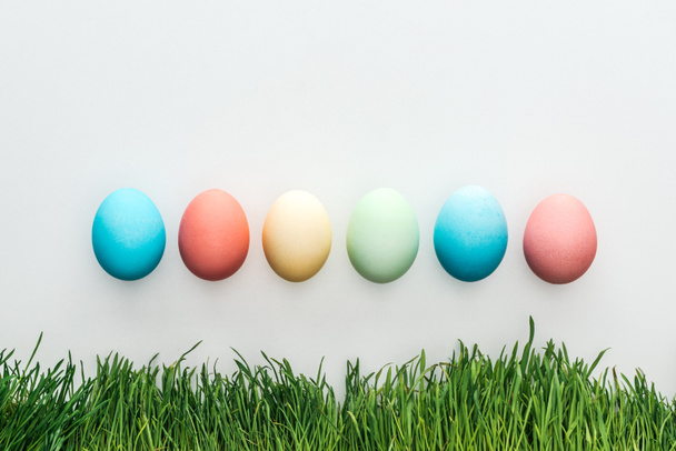 top view of colorful easter eggs isolated on grey with grass - Fotoğraf, Görsel