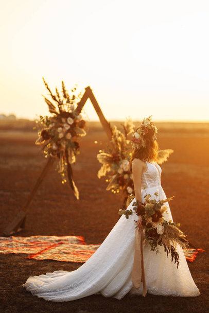Amazing bride in sunset light. Pretty bride. Boho style. Bride wearing fashion wedding dress with feathers with luxury delight make-up and hairstyle. - Foto, imagen