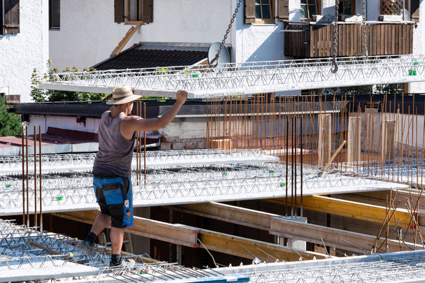 Pracownik prowadzi malejącej betonowej na placu budowy. - Zdjęcie, obraz