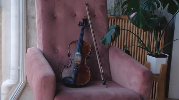 Geige mit Bogen liegender Stuhl im Raum neben Fenster. Ständiger Nockenschuss. - Filmmaterial, Video