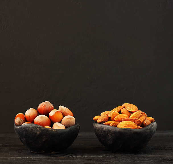 Variety of nuts - almond and hazelnuts on the dark background with copy space - Foto, Bild