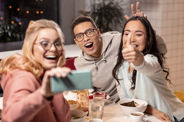 Two girls and boy taking selfie at the table after eating. - Foto, Bild