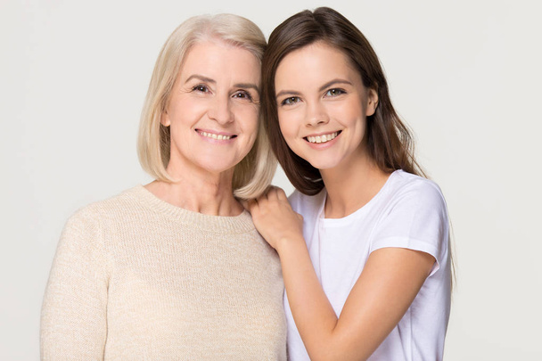 Smiling adult daughter and old mother bonding isolated on background - Photo, Image