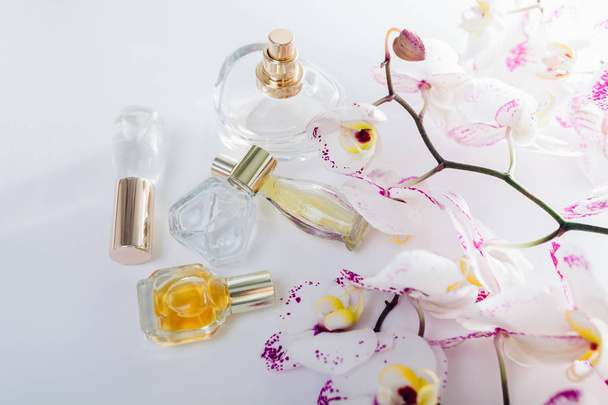 Frascos de perfume con orquídea blanca con manchas moradas sobre fondo blanco
 - Foto, imagen