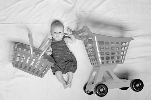 Helping to mommy. Portrait of happy little child. Sweet little baby. New life and birth. Shopping cart. Householder. Family. Child care. Small girl go shopping. Childhood happiness. Big sale offer - Zdjęcie, obraz