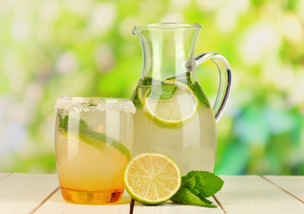 Citrus lemonade in pitcher and glass on wooden table on natural background - Foto, Bild