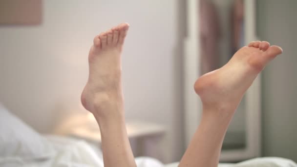 elegante Frauenbeine, die sich auf dem Hintergrund des Schlafzimmers bewegen. Nahaufnahme weiblicher Füße - Filmmaterial, Video