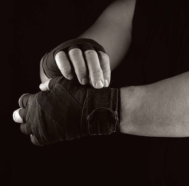 Hombre envuelve sus manos en vendaje textil negro para deportes
 - Foto, Imagen