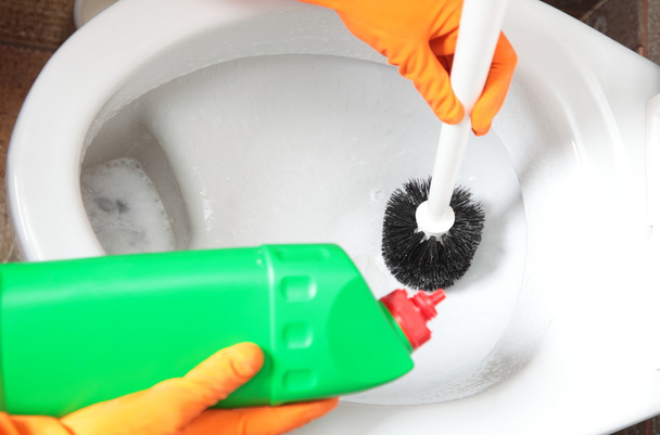 Gloved hand cleaning toilet bowl using brush - Foto, afbeelding