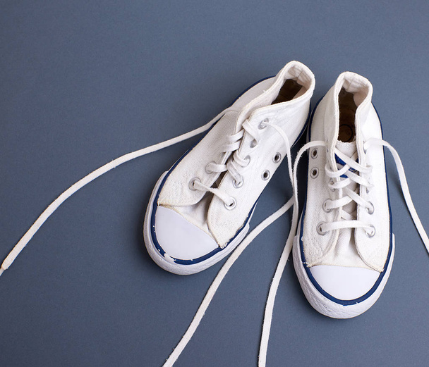 pair of white old textile sneakers with untied laces  - Photo, Image