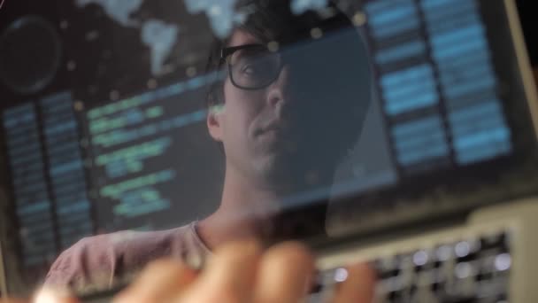 Podwójna ekspozycja: mężczyzna programista w okularach pracujących na laptopie. Programista pisze niebieski kod, odbicie w monitorze - Materiał filmowy, wideo