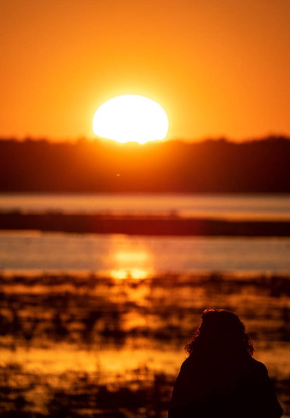 Frauensilhouette beobachtet Sonnenaufgang über dem See - Foto, Bild