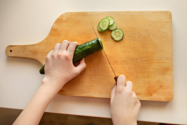 Chica corta pepino en una tabla de madera. Primer plano, cocina, manos, k
 - Foto, Imagen