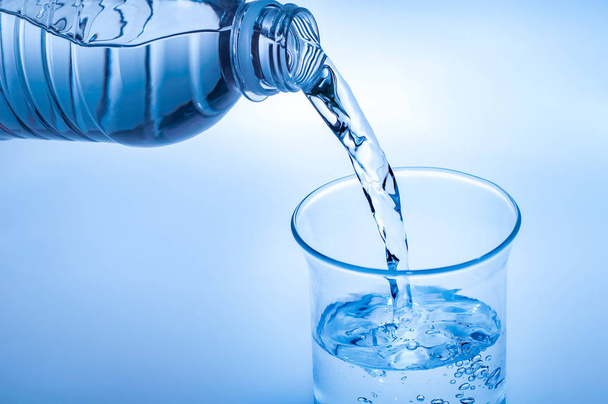Bere acqua versando in vetro su sfondo azzurro
 - Foto, immagini