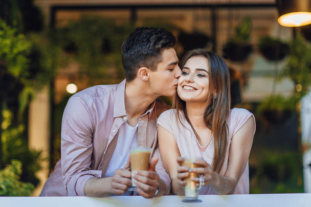 young couple in casual clothes kissing on summer terrace of restaurant  - Photo, Image