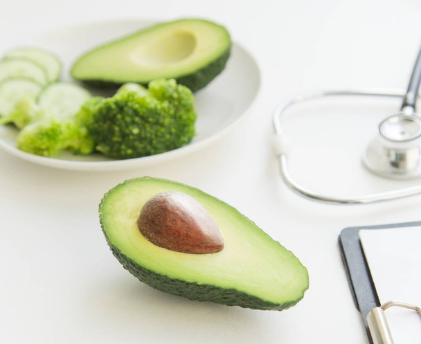 doctor nutritionist table. Healthy and healthy food, broccoli, pickers and avacado. Stethoscope and diet pills. - Foto, Bild