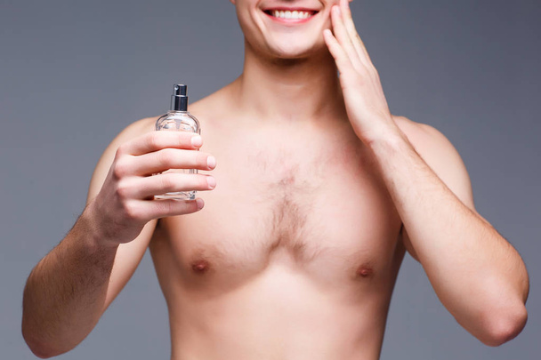 cropped view of man holding perfume on gray background - Foto, Bild