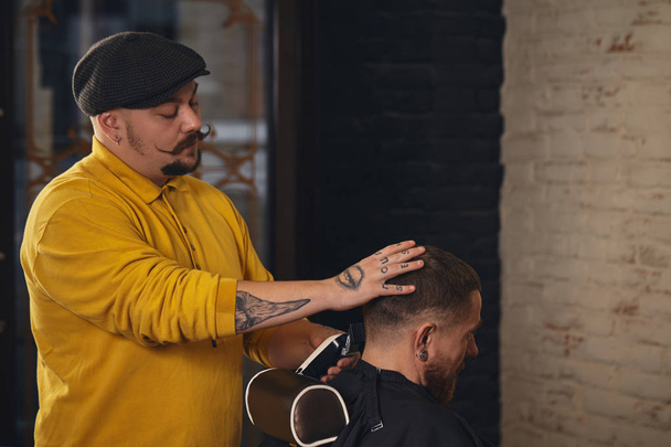 Friseur schneidet attraktiven bärtigen Mann im Friseursalon - Foto, Bild