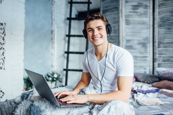 Man using laptop on bed, focus on foreground - Fotoğraf, Görsel