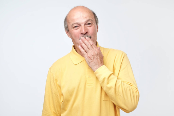 Mature bald man covering mouth and laughing. - Valokuva, kuva