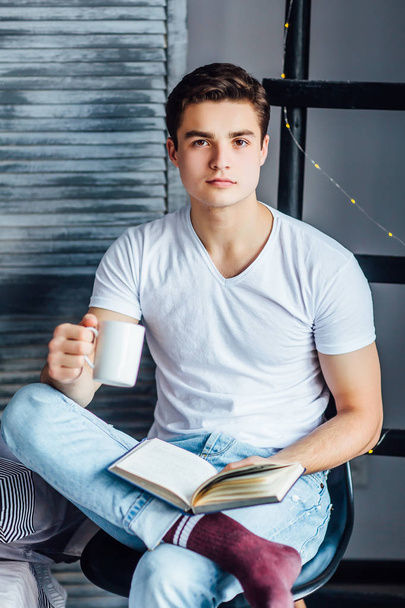 man sitting on chair and reading literature with cup of coffee  - Photo, Image