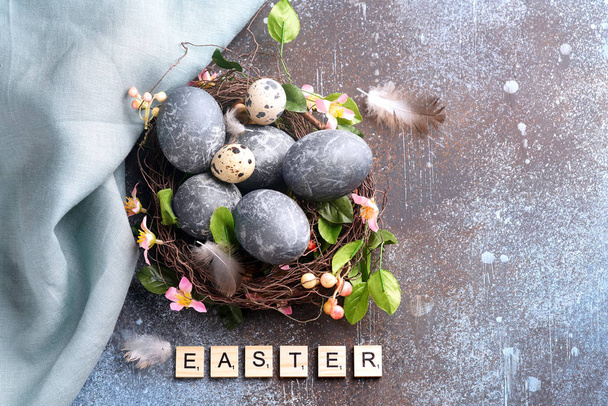 Blue easter egg in nest with flowers on dark vintage background - Photo, Image