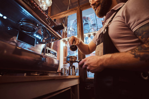 Düşük açılı fotoğraf gülümseyen bir barista kahve dükkanında çalışan bir portafilter holding - Fotoğraf, Görsel
