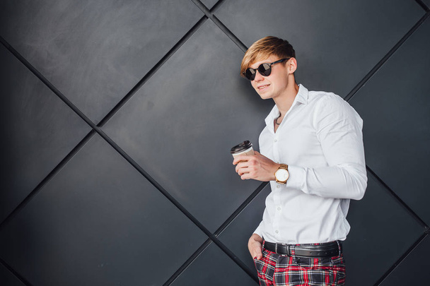 Man in sunglasses and white shirt holding cup of coffee and smiling  - Foto, Imagem