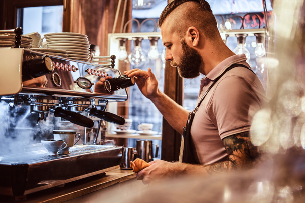 Barista en uniforme preparando una taza de café para un cliente en la cafetería
 - Foto, Imagen