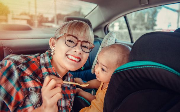 Mulheres asiáticas estão cuidando de seu filho em seu carro
. - Foto, Imagem