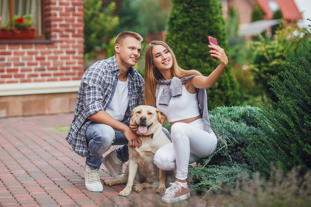 Young beautiful couple with dog taking selfie, focus on foreground - Foto, Imagen