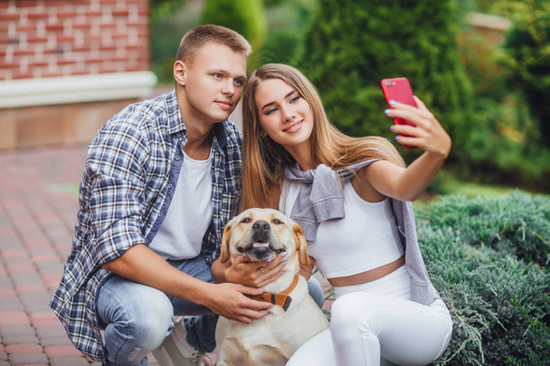 Young happy couple with labrador making photo at park - Foto, Bild