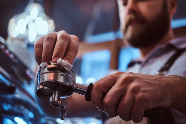 Photo en angle bas d'un barista nettoie le portafilter avant de préparer le cappuccino dans un café ou un restaurant
. - Photo, image
