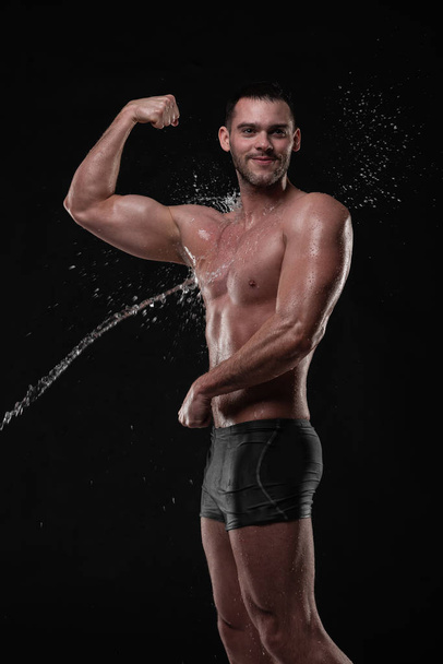 Handsome young man posing with water splashes on face and chest in Studio shot - Fotó, kép