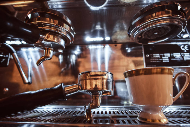 Close-up de um portafilter e xícara com cappuccino ao lado de uma máquina de café no restaurante de um café
 - Foto, Imagem