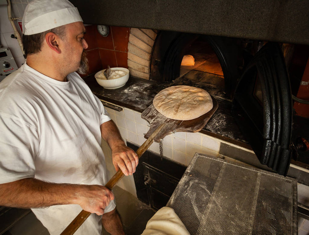 Výroba pečeného chleba s pecí na dřevo v pekárně. - Fotografie, Obrázek