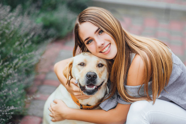 Young woman with retriever in summer park, focus on foreground - Photo, Image