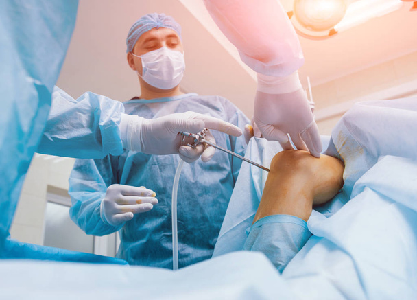 Arthroscope surgery. Orthopedic surgeons in teamwork in the operating room with modern arthroscopic tools. Knee surgery. Hospital background - Fotografie, Obrázek