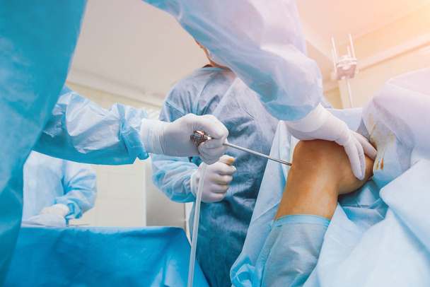 Arthroscope surgery. Orthopedic surgeons in teamwork in the operating room with modern arthroscopic tools. Knee surgery. Hospital background - Photo, image