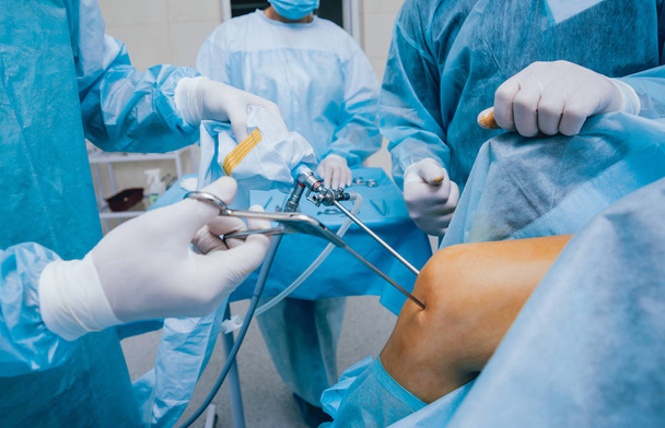 Arthroscope surgery. Orthopedic surgeons in teamwork in the operating room with modern arthroscopic tools. Knee surgery. Hospital background - Fotoğraf, Görsel