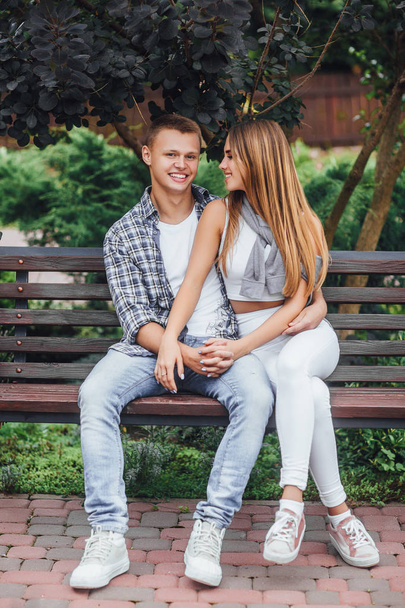 Young couple sitting on bench at park and looking at each other - Fotografie, Obrázek