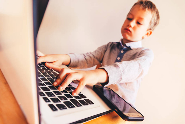 Kind, das in seinem Geschäft mit dem Computer arbeitet, konzentriert - Foto, Bild