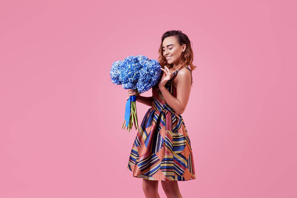 Cheerful young lady in stylish fashionable dress being excited to get bouquet of spring flowers on women's day isolated over pink background.  - Φωτογραφία, εικόνα