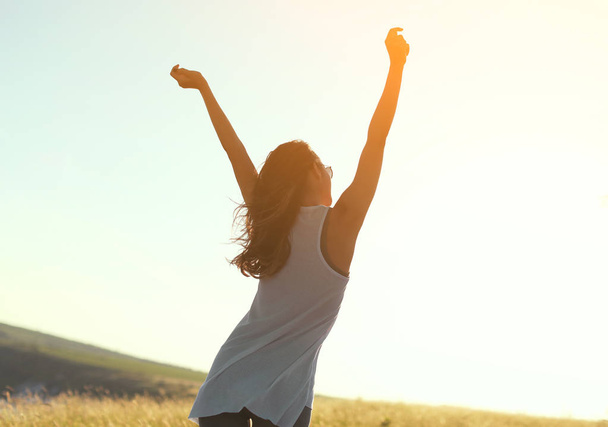 Ευτυχισμένος κορίτσι με τα χέρια υψωμένα στον ήλιο  - Φωτογραφία, εικόνα
