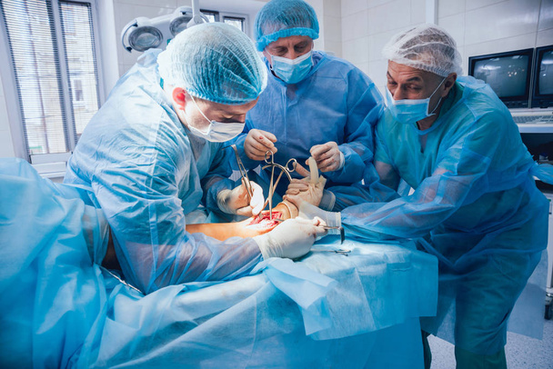 Process of trauma surgery operation. Group of surgeons in operating room with surgery equipment. Medical background - Φωτογραφία, εικόνα