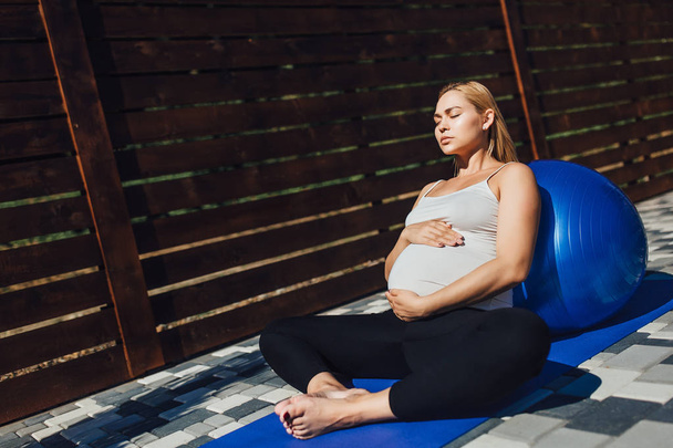 hamile kadın meditasyon yoga mat lotus pozisyonda - Fotoğraf, Görsel