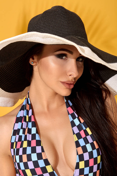 Young sexy confident brunette woman posing before camera, wearing bikini and big nice black hat - Foto, Bild