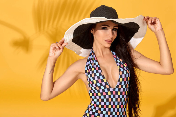Giovane sexy donna bruna fiduciosa posa prima della fotocamera, indossando bikini e grande bel cappello nero
 - Foto, immagini