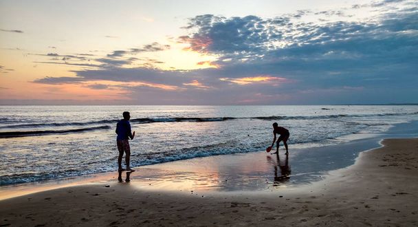coucher de soleil : deux frères jouent à la pagaie sur la plage
 - Photo, image