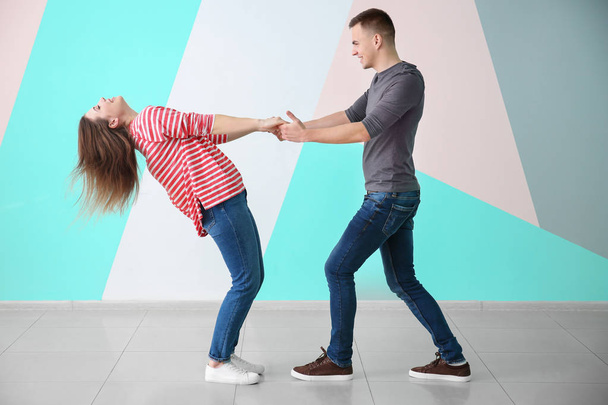Young couple dancing together against color wall - Фото, изображение